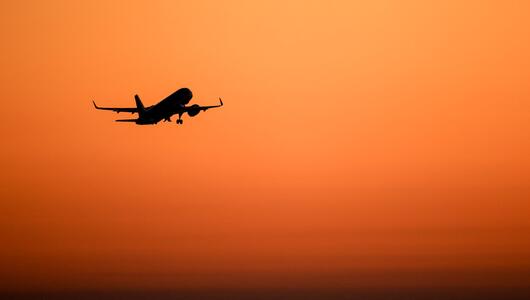 Ein Flugzeug hebt vor orangefarbenem Himmel ab