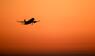Ein Flugzeug hebt vor orangefarbenem Himmel ab