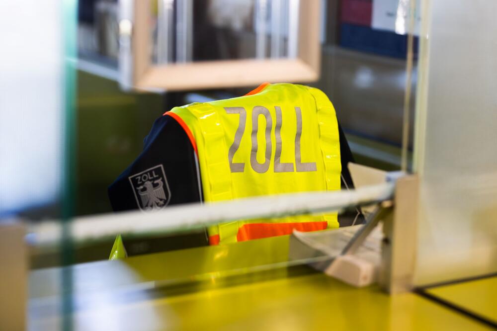 Warnweste mit der Aufschrift "Zoll" hängt über einem Stuhl