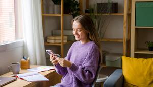 Eine Frau sitzt an ihrem Schreibtisch und hat einen Taschenrechner in der Hand.