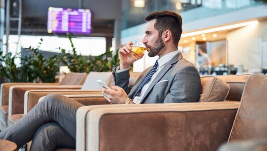 Mann trinkt ein Glas Alkohol am Flughafen