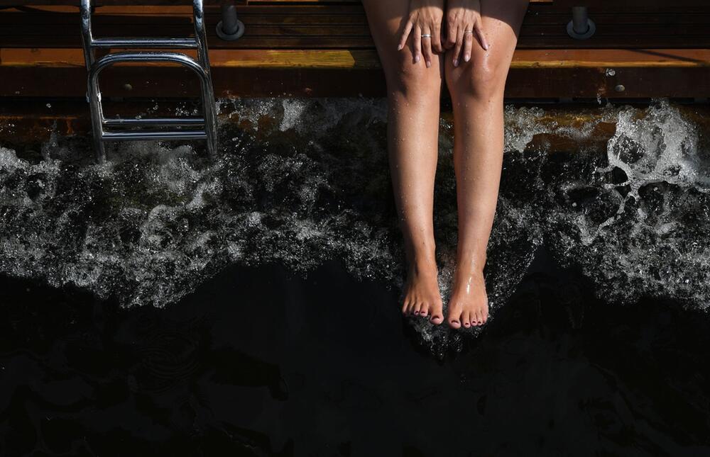 Frau lässt ihre Füße von einem Hausboot im Wasser baumeln