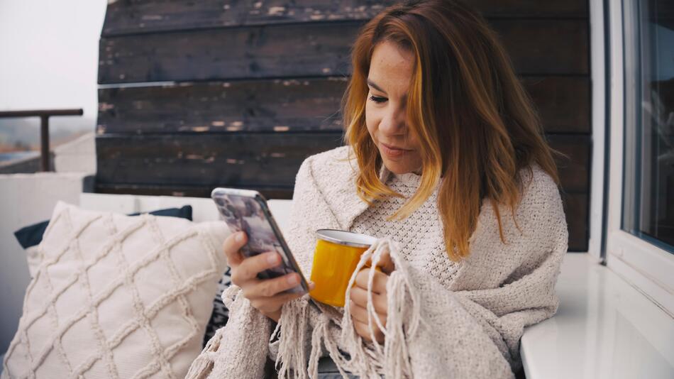 Frau mit Tasse und Smartphone