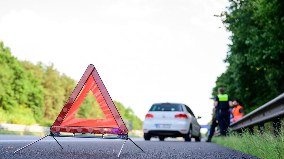 Mit Warndreieck steht nach einer Panne auf der Autobahn