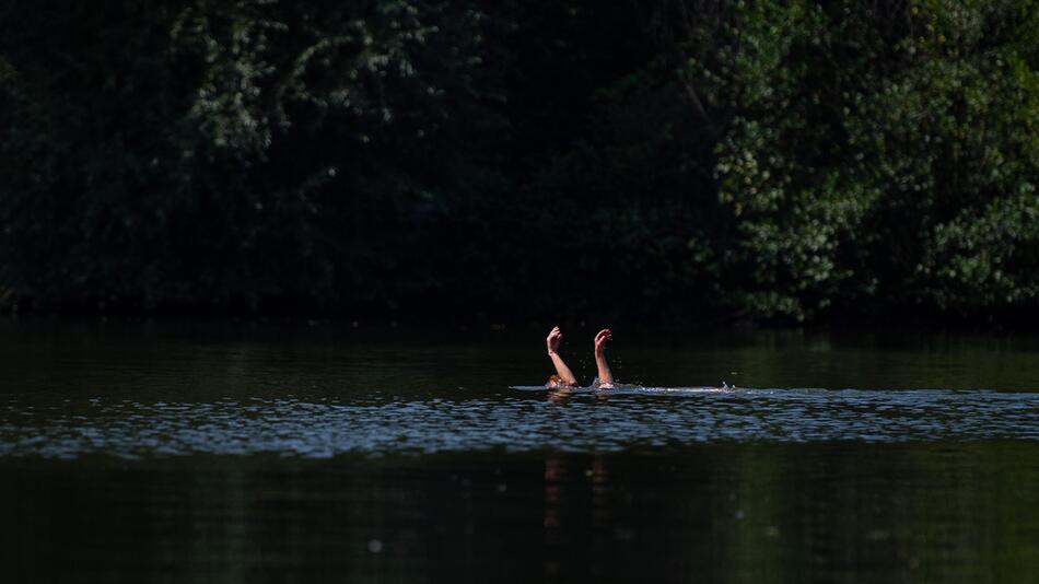 Eine Schwimmerin streckt die Hände aus dem Wasser