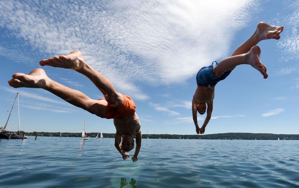 Zwei junge Männer springen am Starnberger See ins Wasser