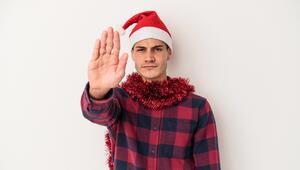 Ein Mann hat eine Weihnachtsmütze auf dem Kopf. Er streckt die flache Hand nach vorne aus.