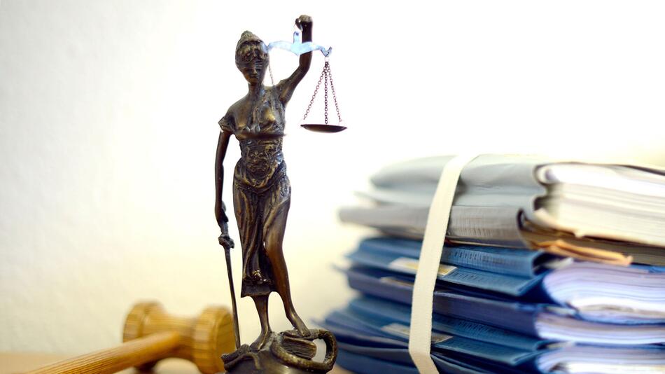 Unterlagen liegen neben einer Nachbildung der Justitia
