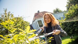 Eine Frau beschneidet einen Strauch mit einer Gartenschere