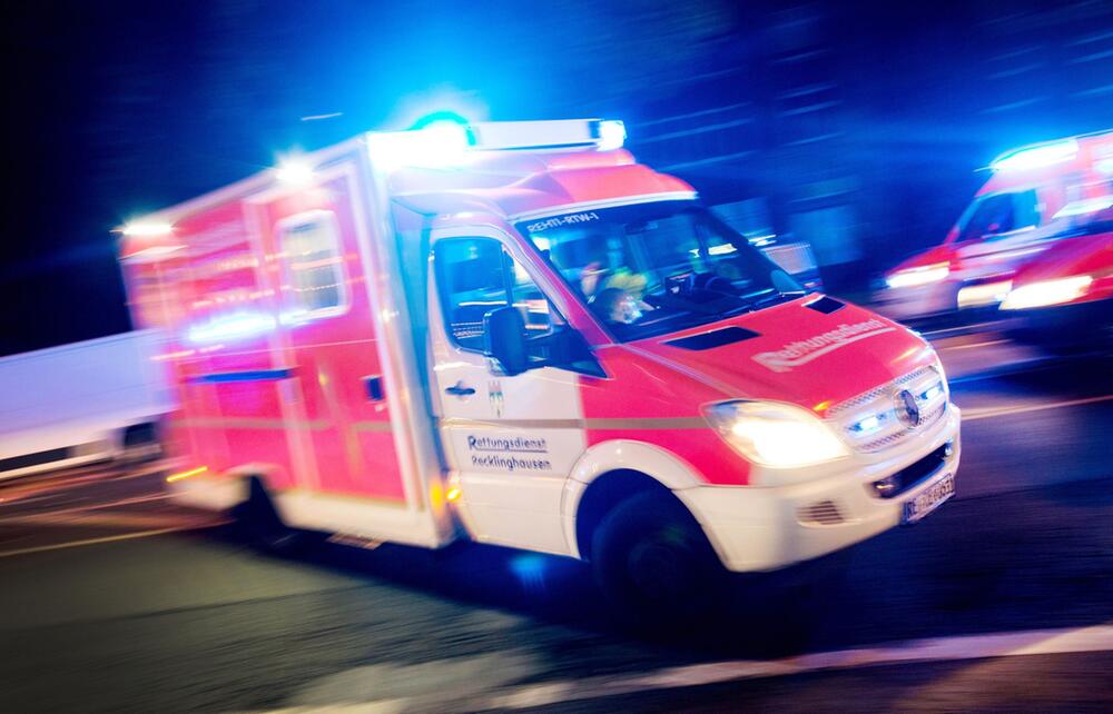 Rettungswagen der Feuerwehr fährt mit Blaulicht durch eine Straße