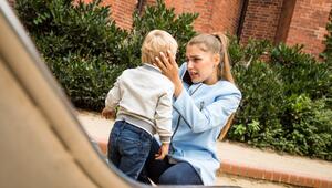 Mutter hält auf dem Spielplatz besorgt den Kopf ihres Kindes