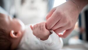 Ein Baby klammert sich an den Finger seiner Mutter
