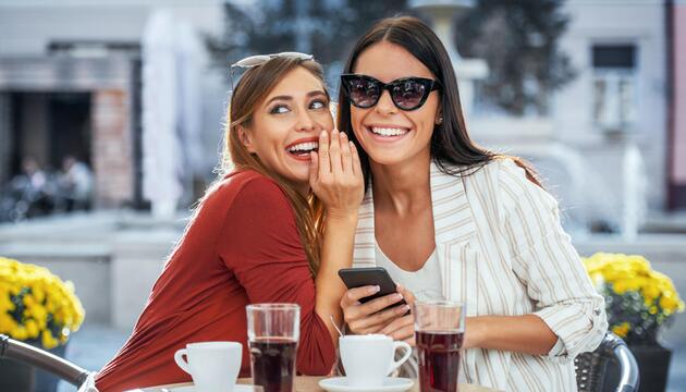 Junge Frauen lachen im Café und Flüstern