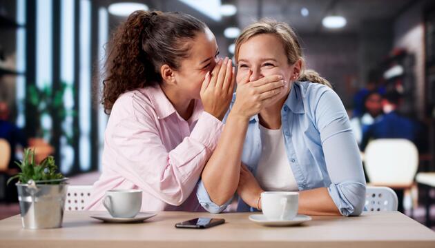 Junge Frauen lachen im Café und Flüstern