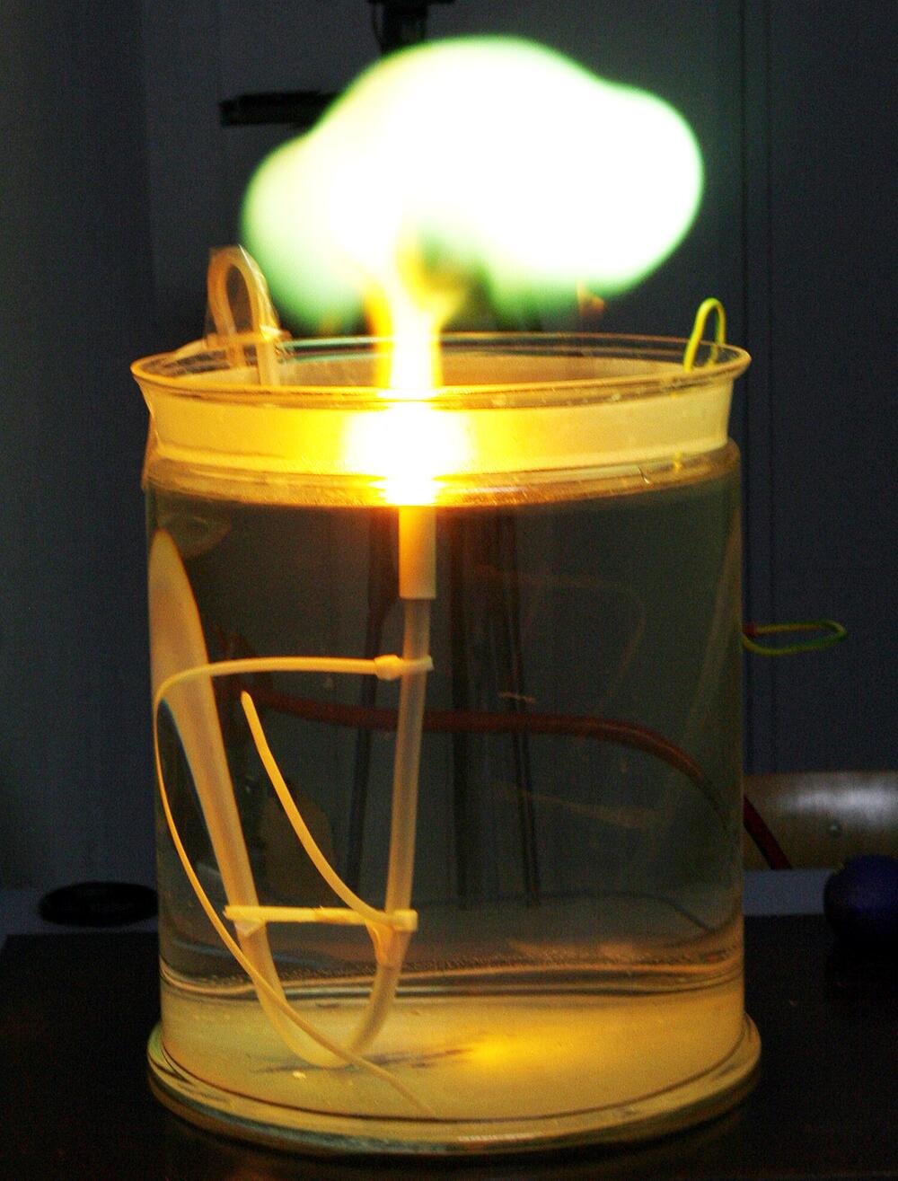 leuchtender Plasmaball steigt über einem Glasgefäß