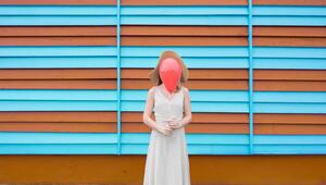 Eine junge Frau hält sich einen Luftballon vors Gesicht