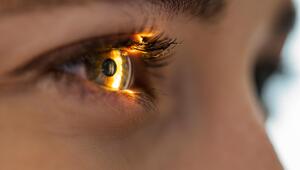 Auge in Nahaufnahme, ein Lichtschein fällt auf die Iris