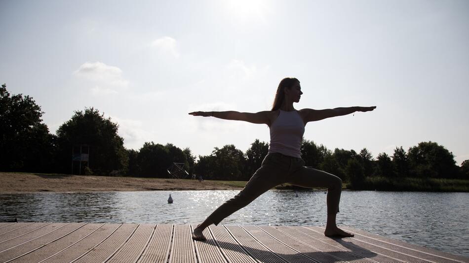 Eine Frau macht Yoga an einem See