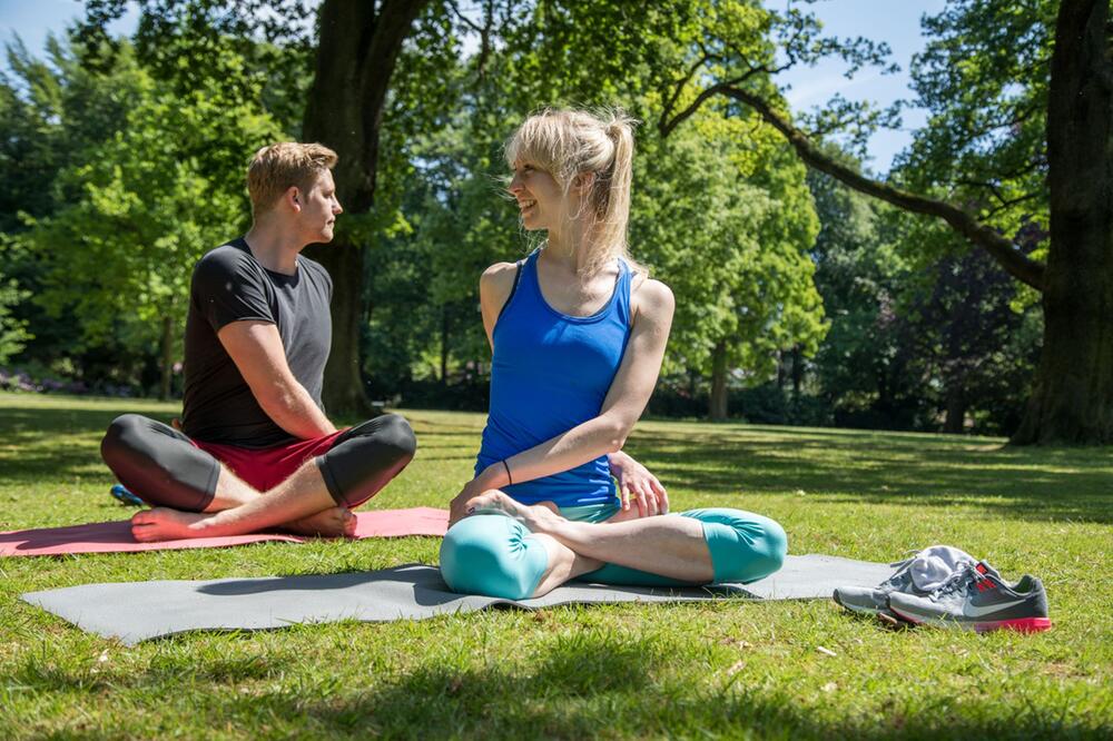 Mann und Frau machen Yoga in einem Park