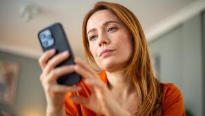 Frau schaut genervt auf ihr Smartphone