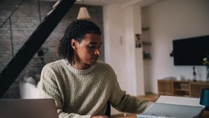 Mann arbeitet am Laptop und blickt in Unterlagen