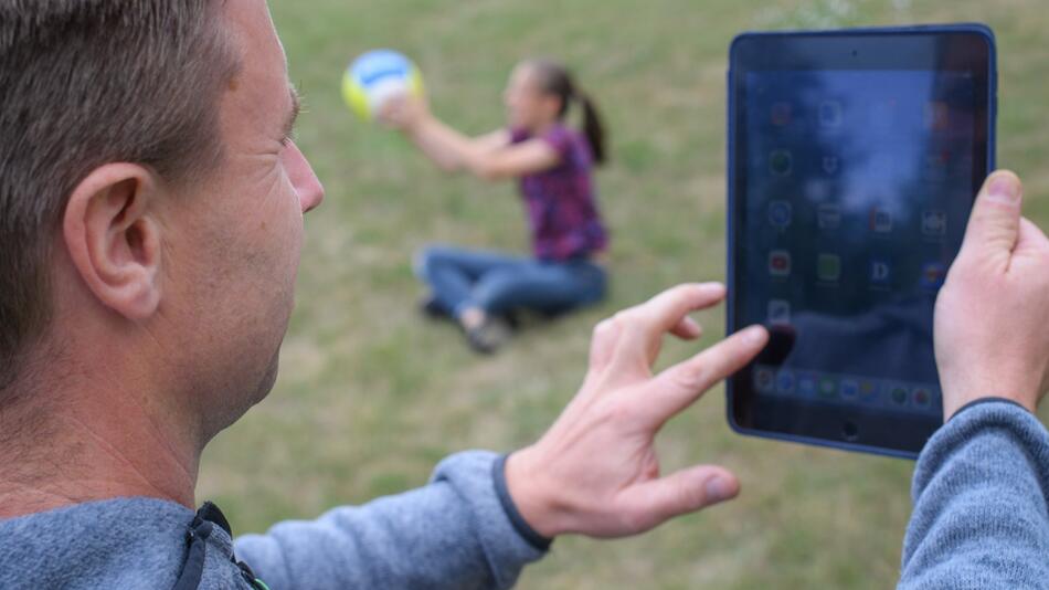 Vater mit Tablet und Kind, das spielt