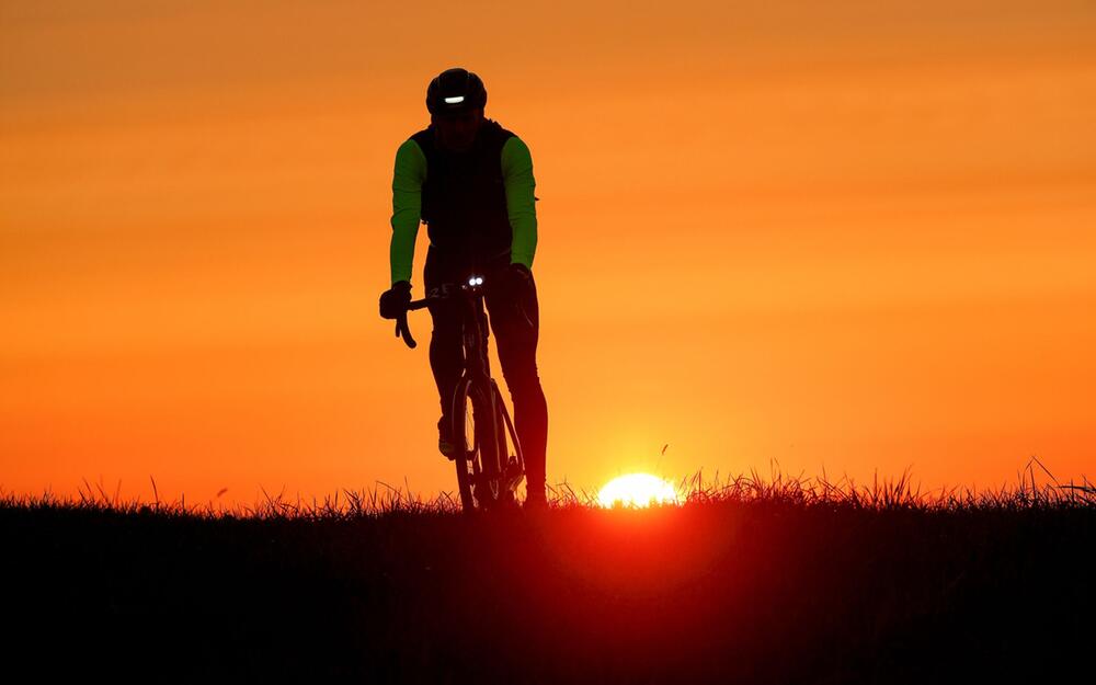 Ein Radfahrer im Gegenlicht der aufgehenden Sonne