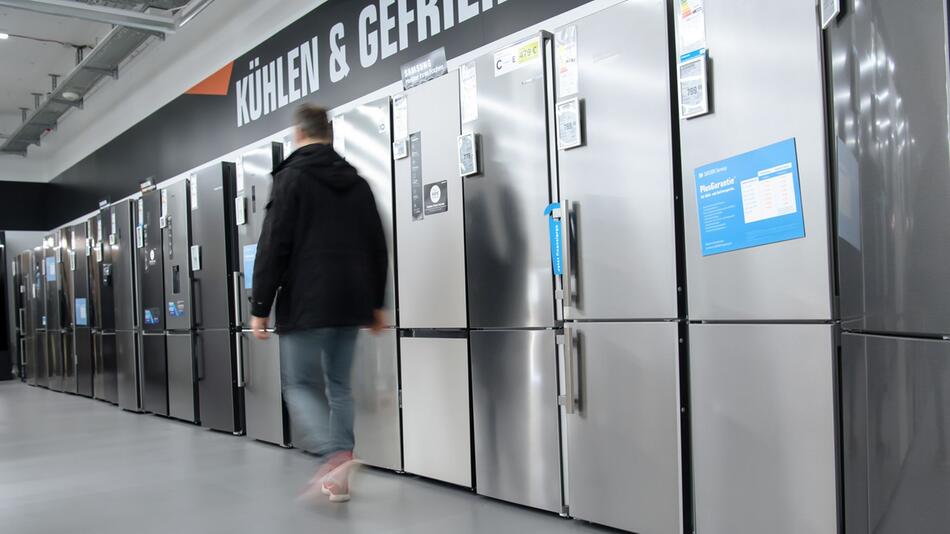Mann geht im Elektronikmarkt an Kühl-Gefrierkombinationen vorbei