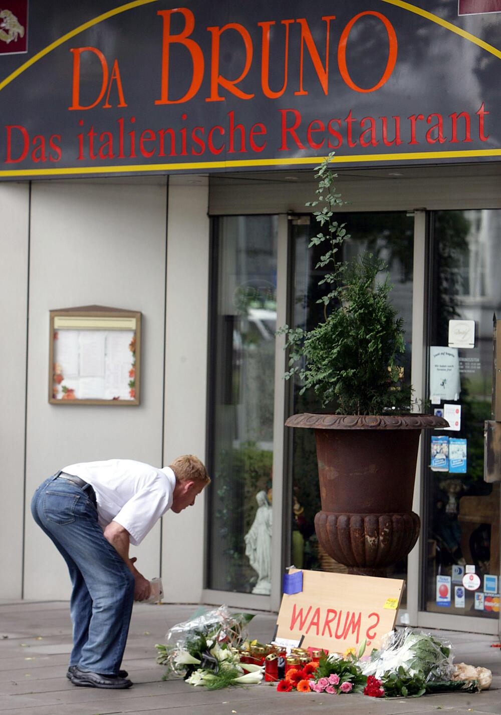 Ein Mann steht vor Blumen am Tatort vor dem Restaurant Da Bruno nach den Mafiamorden 2007.