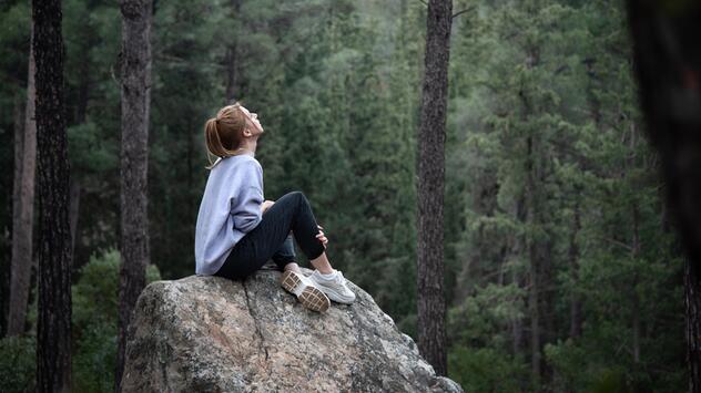 Frau sitzt auf felsen im Wald