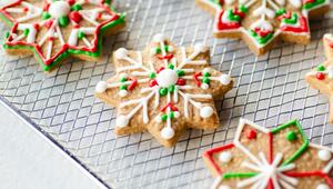 Mehrere sternförmige Weihnachtsplätzchen auf einem Metallgitter, verziert mit weißem, rotem und ...