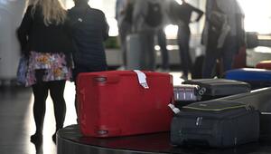 Passagiere warten am Gepäckband auf ihre Koffer