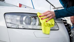 Eine Frau reinigt die Scheinwerfer ihres Autos