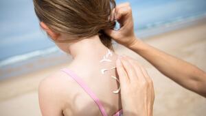 Eine Frau cremt ihre Tochter mit Sonnencreme ein