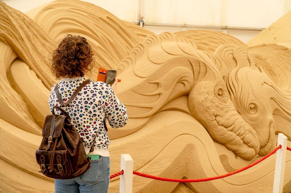 Besucherin fotografiert eine Sandskulptur bei der SandWorld