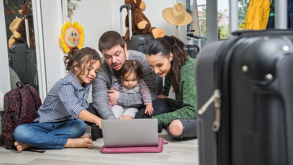 Familie plant mit Laptop ihren Urlaub