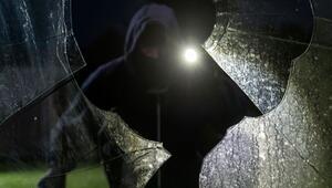 Durch eine eingeschlagene Scheibe blickt ein fiktiver Einbrecher