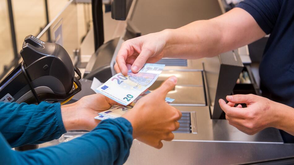 Frau hebt Geld im Supermarkt ab