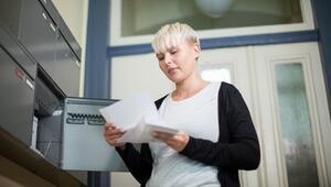 Frau holt Post aus einem Briefkasten