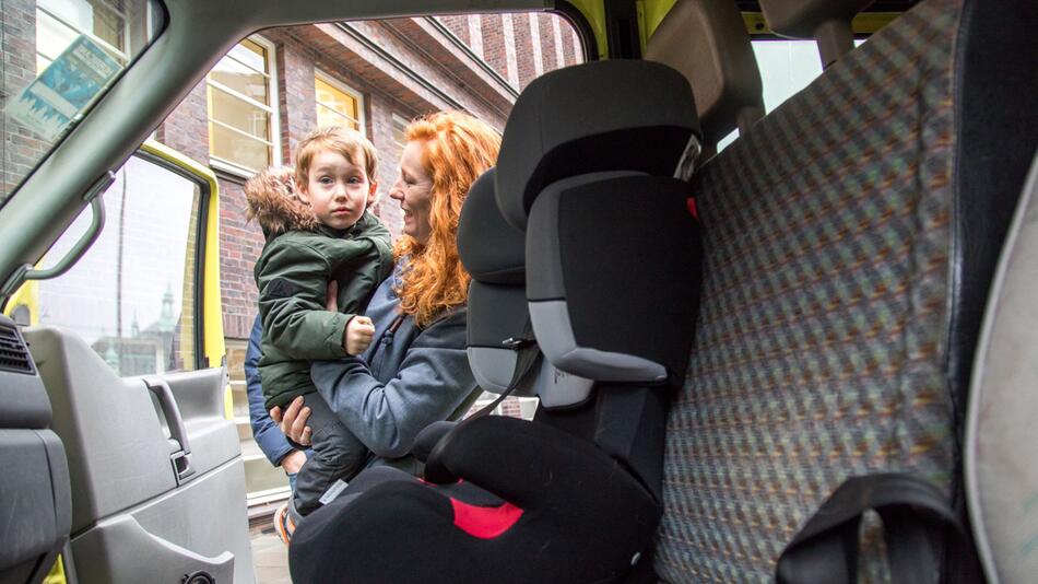 Frau setzt Sohn in den Kindersitz ihres Autos