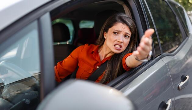 Frau im Auto regt sich über anderen Verkehrsteilnehmer auf.
