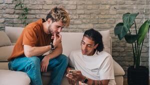 Zwei junge Männer mit Smartphone auf einer Couch