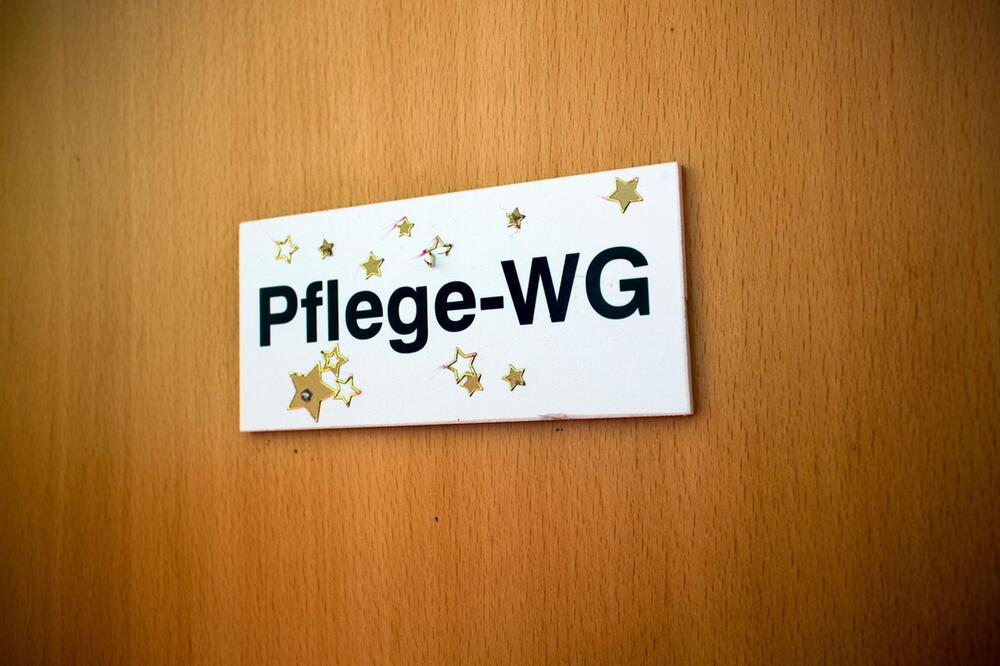 Schild "Pflege-WG" hängt an einer Tür