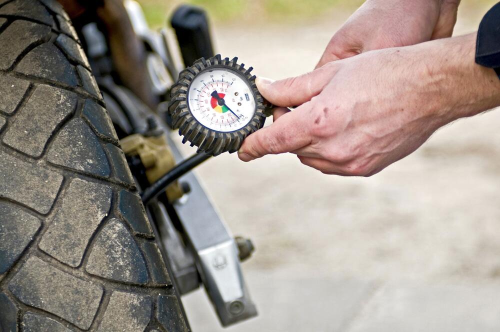 Ein Mann prüft den Reifendruck seines Motorrads