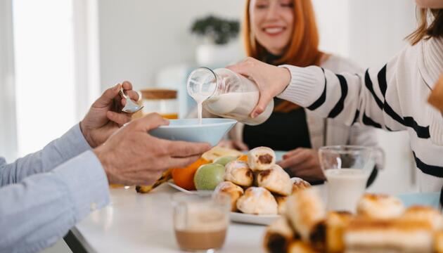 Eine Frau gießt einem Mann Milch in die Müslischüssel