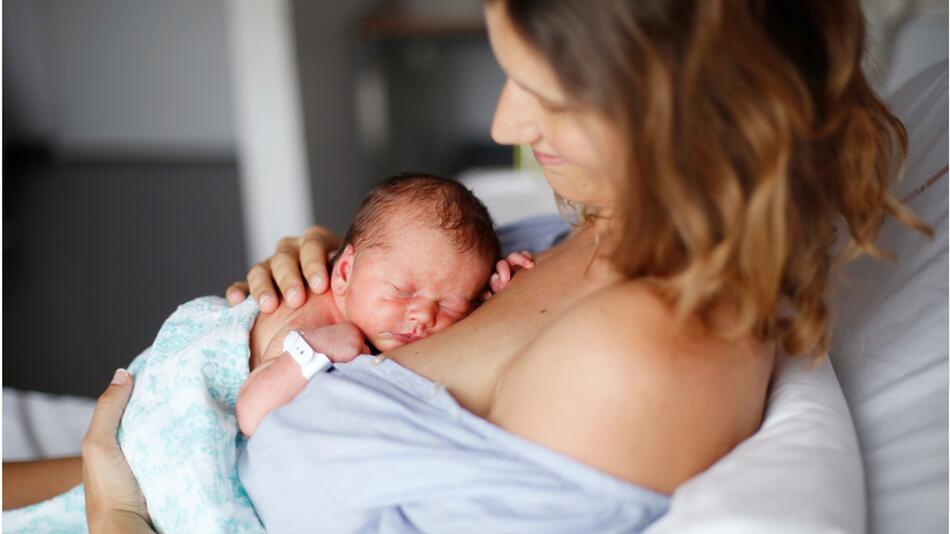 Neugeborenes liegt auf seiner Mutter