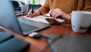Frau sitzt mit einem Laptop am Tisch