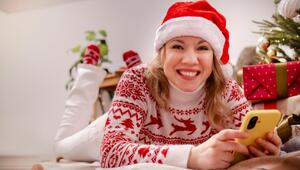 Frau mit Weihnachtsmütze und Smartphone, die lächelt 