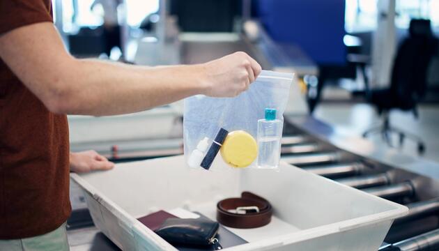 Passagier mit Plastikbeutel bei Sicherheitskontrolle.