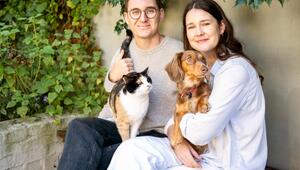 Ein Mann und eine Frau mit einer Katze und einem Hund auf dem Arm.